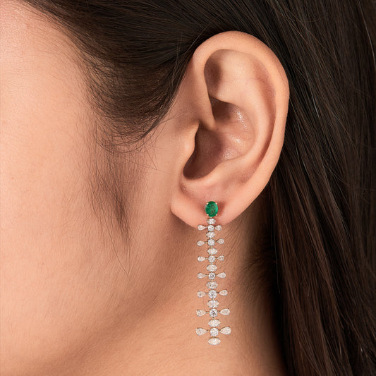 Oval emerald and diamond drop earrings in 14K gold, seen from the side.