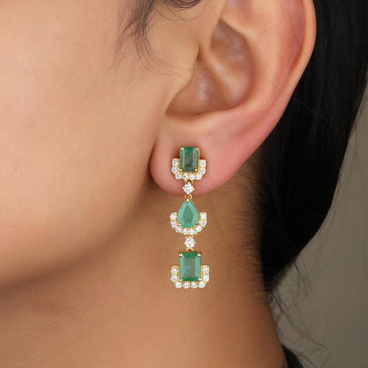 Emerald and diamond drop earrings in 14K yellow gold, seen from the side.