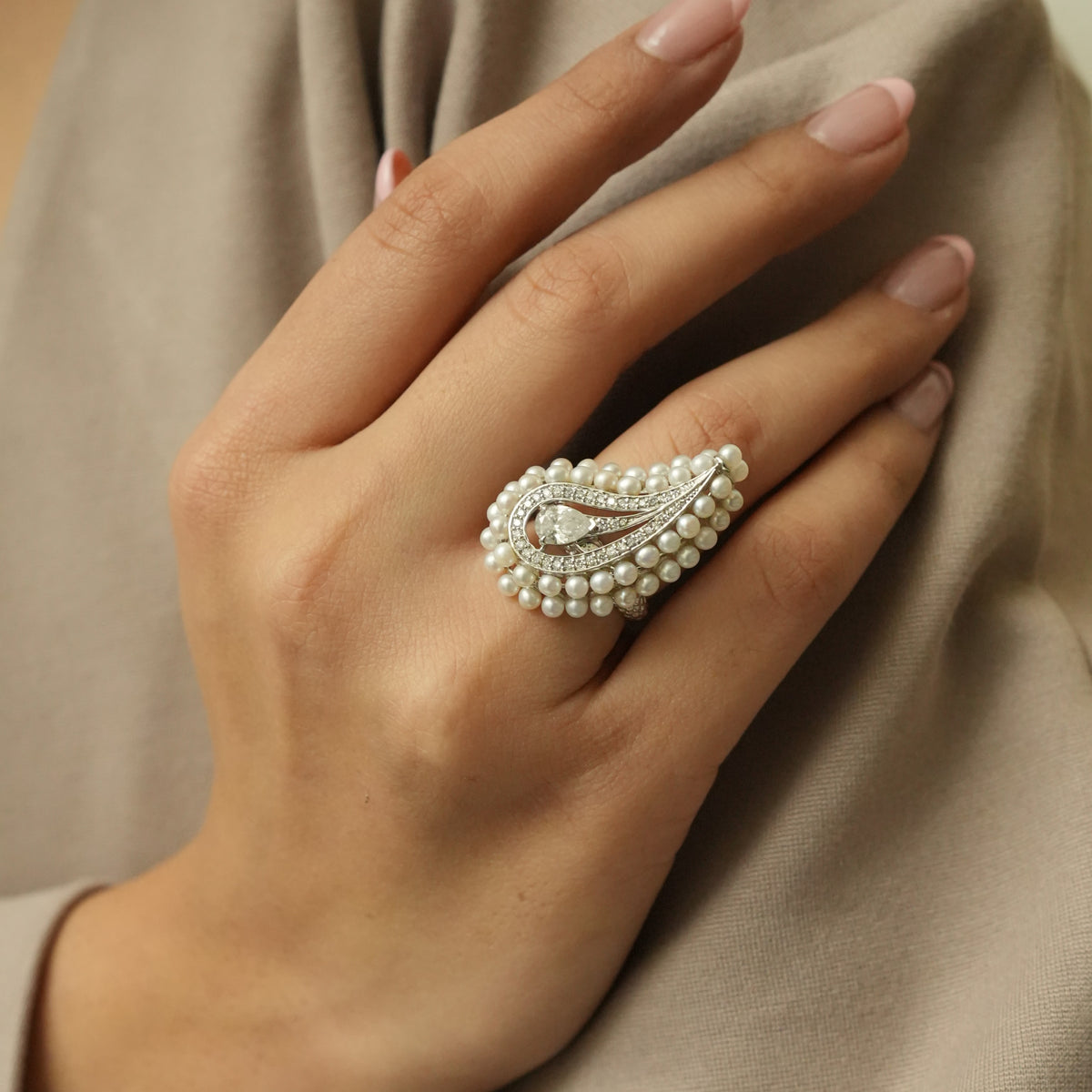 Close-up of the pear centre diamond framed by pavé diamonds and round white pearls