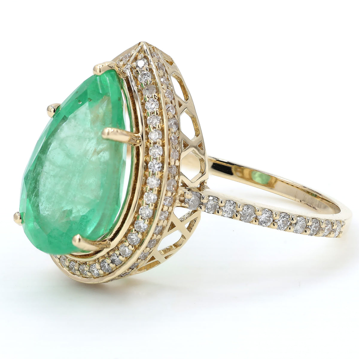 Close-up of the diamond halo — 14K yellow gold ring framing a pear-cut natural emerald